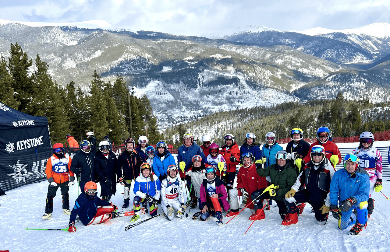 Skiers and snowboarders pose together on a snowy slope at Keystone Resort, surrounded by scenic mountains, showcasing camaraderie and winter sports excitement.